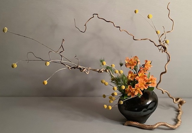 Sogetsu ikebana flower arrangement featuring orange and yellow flowers in a vase