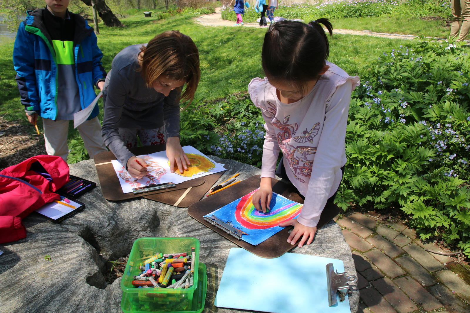 Children making art with crayons while outside on a spring day