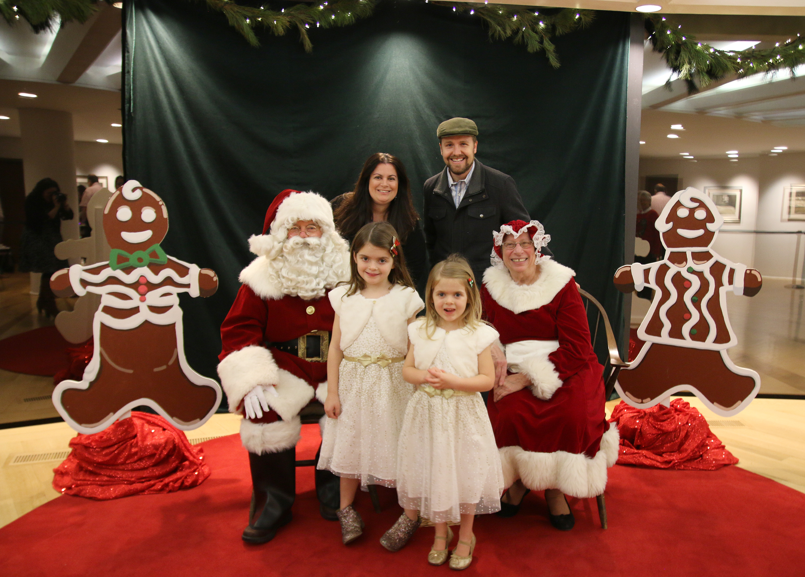 A young family posing for a picture with Santa and Mrs. Claus at the Children's Christmas Party