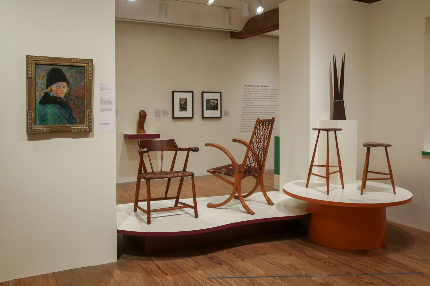 Installation view of exhibition with furniture, paintings, and prints.