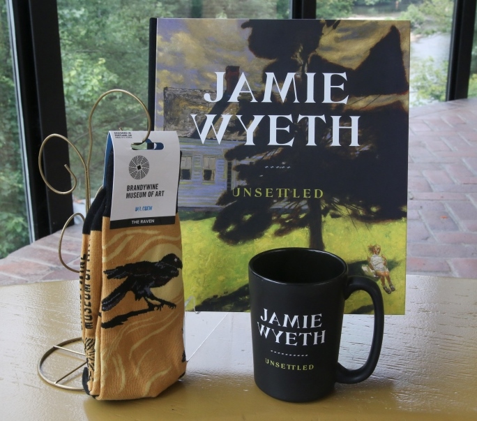 Photo of a Jamie Wyeth exhibition catalogue, mug, and socks in front of window