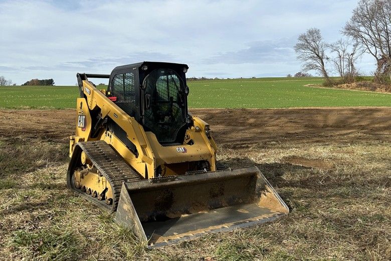 A large piece of farm machinery clears the land on a farm in winter