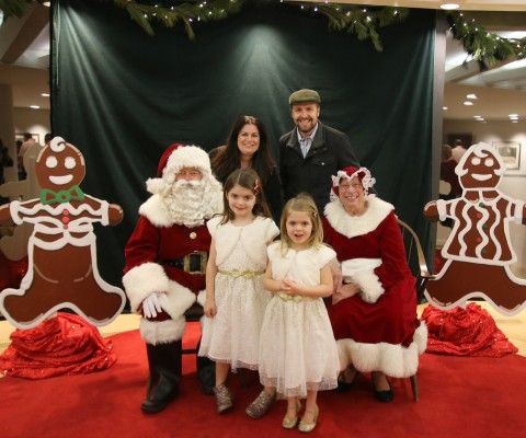 A young family posing for a picture with Santa and Mrs. Claus at the Children's Christmas Party