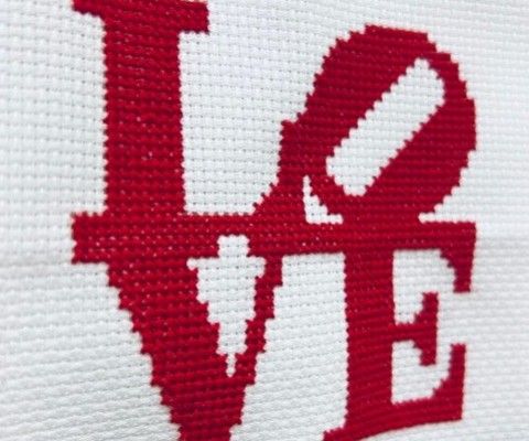 A cross-stitch pattern featuring the word "Love" in red thread on a white background