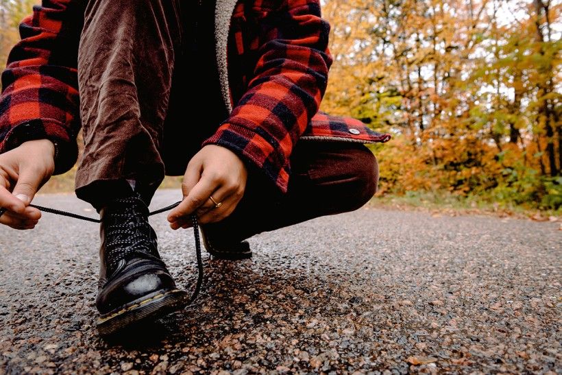 Photo of person tying a pair of hiking boot laces. Photo by Harrison Haines