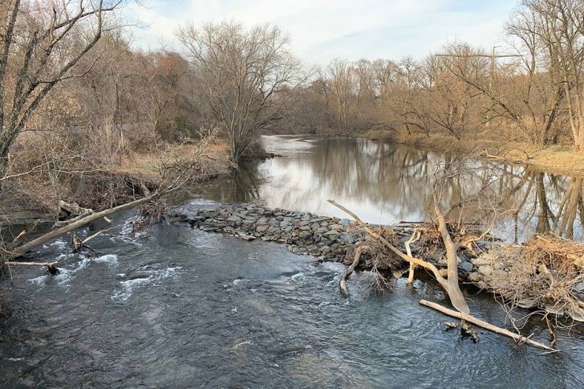 landscape photo of a low head dam seen from a bridge in winter