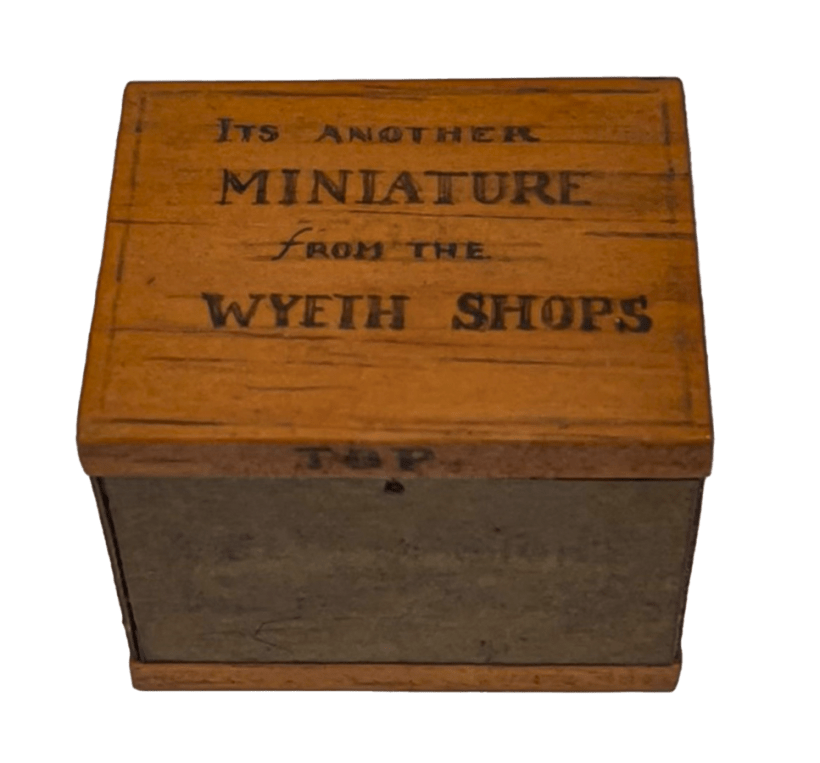 A small wood box with the words "It's another miniatures from the Wyeth Shops" written on the lid.