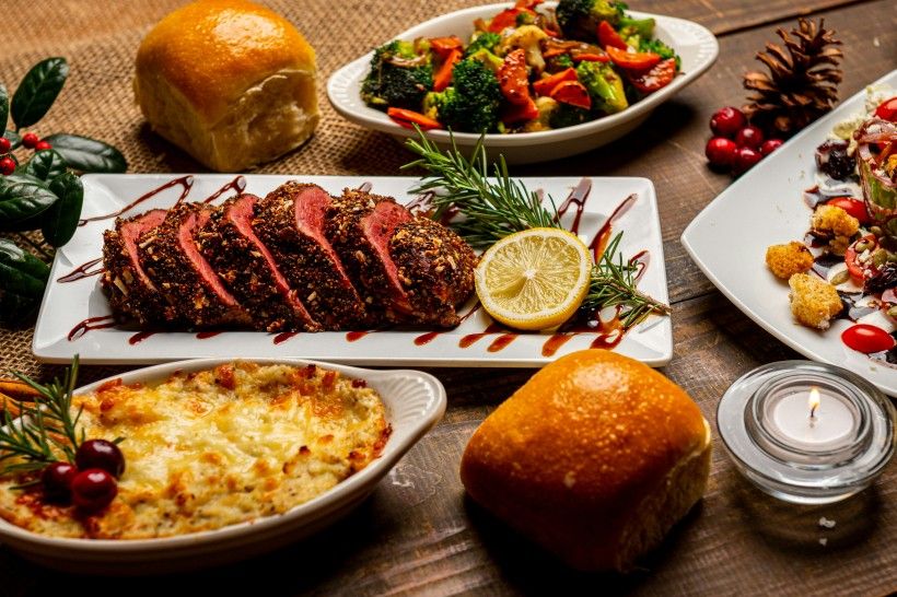 photo of a holiday dinner spread with a roast, casserole and roasted vegetables