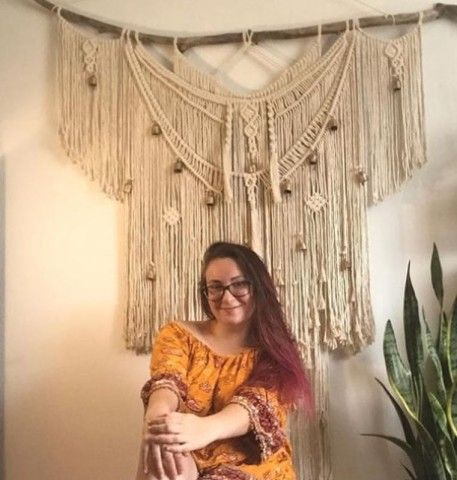 Woman sitting in front of a large macrame work.